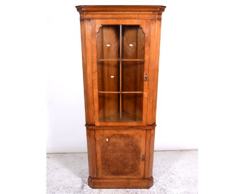 Reproduction walnut corner cabinet, moulded cornice, plain frieze, the upper section glazed enclosed door enclosing shelves, 