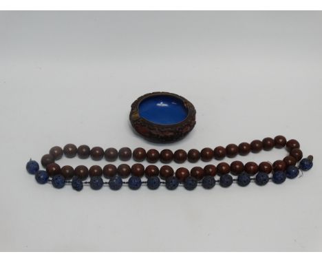 A string of pierced blue enamel beads - length 23cm, together with a string of polished hardwood beads and a red lacquer and 