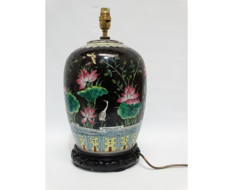 A Chinese 20th century vase - converted to a lamp, decorated with aquatic flowers and foliage on a black ground and raised on