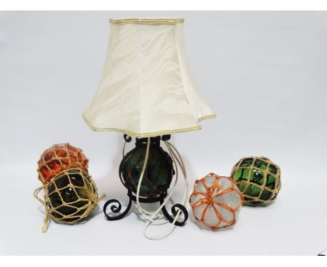 Five early 20th century glass fishing floats - three green, one amber and a clear glass example, one of which had been incopo