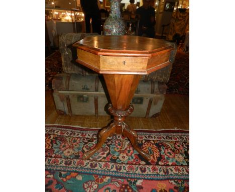 A mid Victorian walnut octagonal trumpet work table, the hinged top enclosing a compartmentalised interior, raised on a tripo