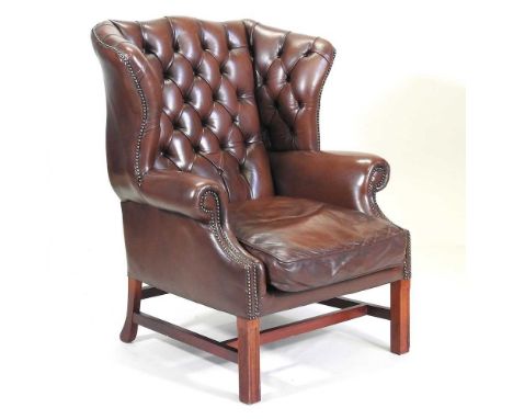 A modern brown leather upholstered button back wingback armchair, on square legs