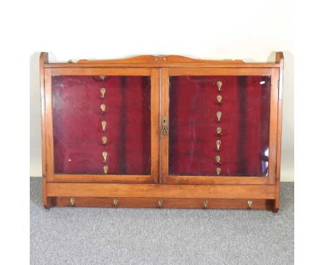 An Edwardian whip rack, enclosed by a pair of glazed doors, 134cm wide
