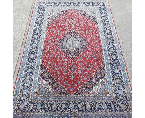 A hand knotted Persian carpet, with a central medallion and all over floral designs, on a red field, 424 x 291cmOverall condi