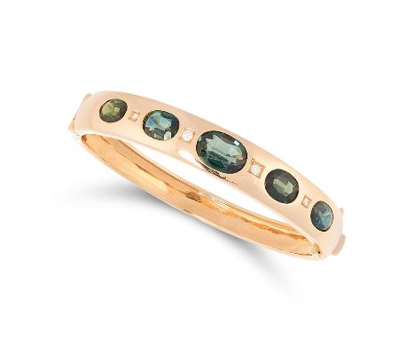 A TOURMALINE AND DIAMOND BANGLE in 18ct yellow gold, set with a row of alternating round cut diamonds and oval cut tourmaline