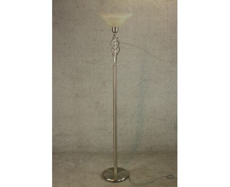 A contemporary polished and brushed steel floor standing uplighter lamp, with a glass shade over spiral decoration on a cylin
