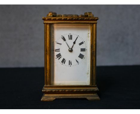 An early 20th century brass cased carriage clock, the white dial with black painted Roman numerals, with swing handle and rai