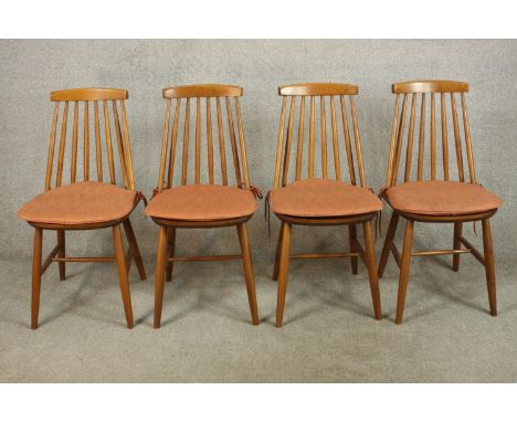 A set of four light elm Ercol stick back Goldsmith dining chairs raised on splayed supports with turned stretcher. 