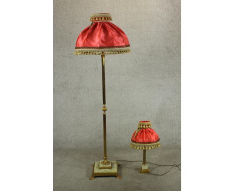 An early 20th century reeded brass standard lamp with red silk shade on stepped onyx base terminating in paw feet together wi