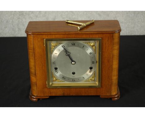 An Art Deco Elliot of London walnut cased mantle clock, the silvered dial with black etched Roman numerals, raised on shaped 