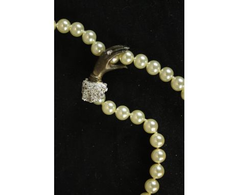 A faux pearl necklace and bracelet with silver clip clasp in the form of a ladies hand, paste set diamond ring on her finger 