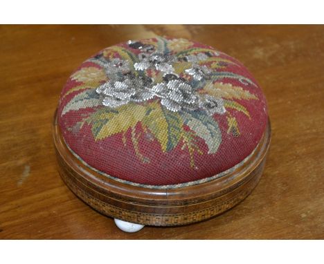 A Tunbridge ware circular footstool, beaded upholstery, ceramic feet.