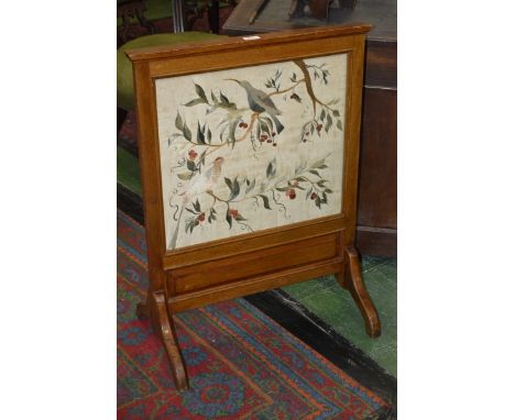 An Arts and Crafts mahogany fire screen, the needlework banner in coloured silks with birds amongst fruiting branches, c.1910