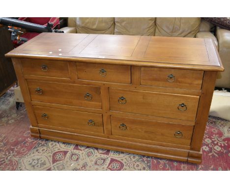 A contemporary light oak sideboard, oversailing top, an arrangement of seven drawers to base, 85cm high, 150cm wide