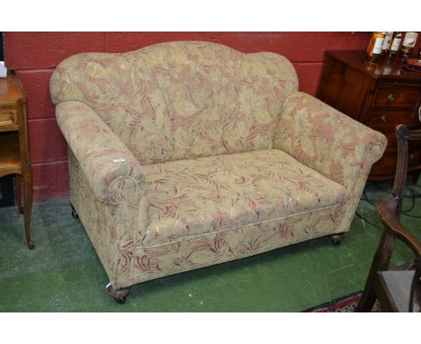 A Victorian drop arm sofa, shaped back, scrolling arms, stuffed-over seat, turned legs