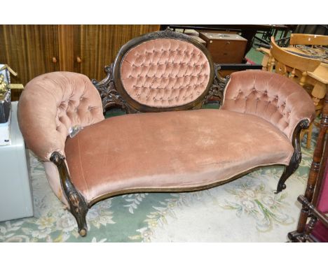 A Victorian sofa, deep button oval back, scrolling arms, carved forelegs.