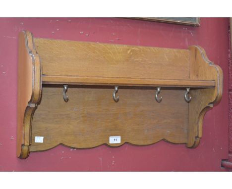 An oak wall shelf with cup hooks.