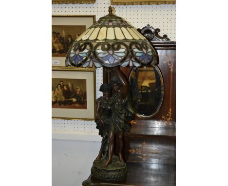 A large figural table lamp with stained glass Tiffany type shade.
