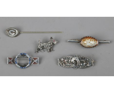 A silver stick pin and three silver brooches, one set with a cowrie shell.