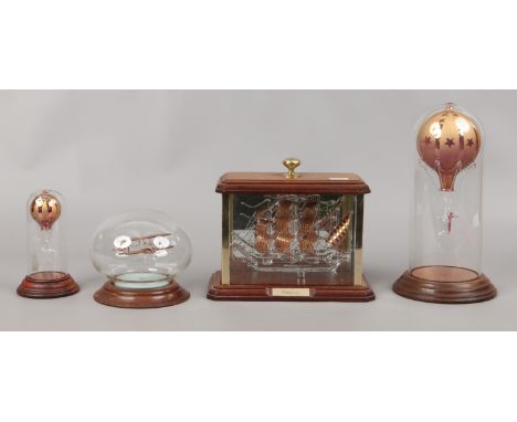 A cased glass model of the Endeavour, two glass models of hot air balloons under glass domes and one of a biplane.