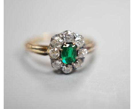 A yellow metal, emerald and diamond set oval cluster ring, size M/N, gross weight 3.1 grams.