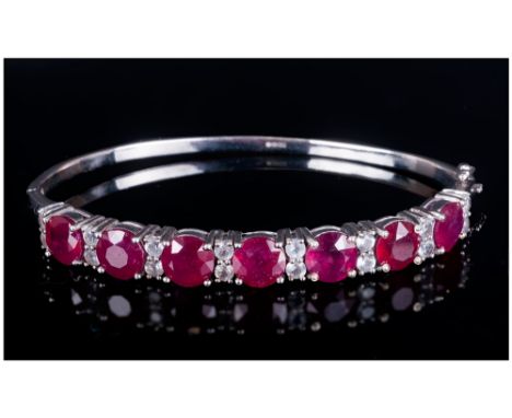 Ruby and White Topaz Bangle comprising a lavish row of seven round cut, rich red, rubies, the birthstone for July, each measu