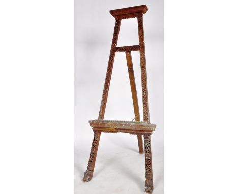 A vintage 20th Century Oriental carved hardwood easel stand of typical form having carved floral uprights raised on elephant 
