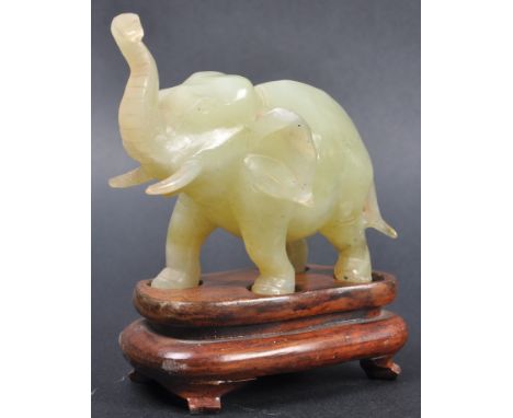 A 20th Century Chinese hand carved jade figurine depicting an elephant. The figure modelled with trunk raised and protruding 