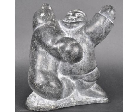 A 20th Century Canadian Inuit Art hand carved soapstone sculpture figurine in the form of&nbsp; man wrestling a seal. Man mod