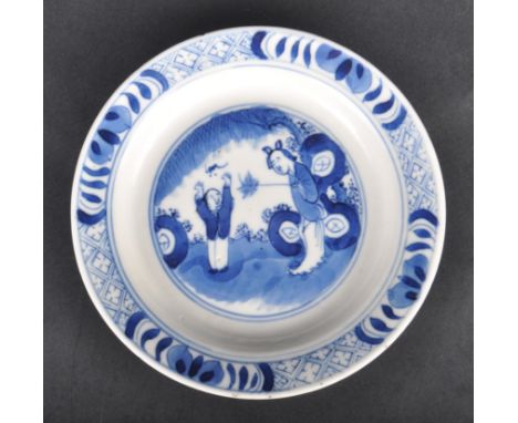 An early 18th Century Kangxi period porcelain plate hand painted in blue and white depicting a central scene with figures in 