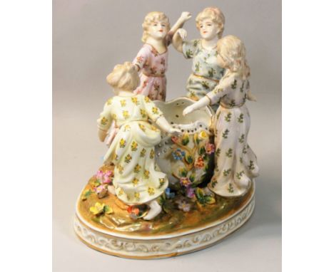 A Meissen 20th century porcelain figure group, modelled as four girls dancing in a circle around a well, on a naturalistic ba