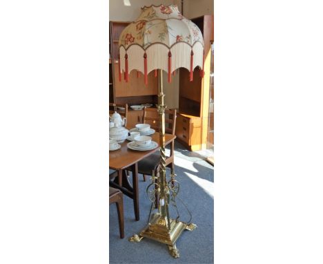 A brass telescopic standard lamp, with square twist stem, floral scroll supports to a stepped base with paw feet, 135 - 150cm