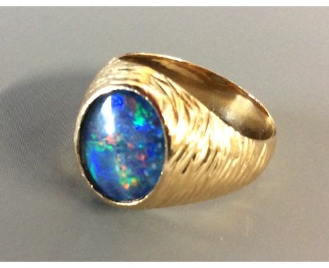 A VINTAGE 9CT GOLD AND DOUBLET OPAL GENTLEMAN'S SIGNET RING Having a cabochon cut opal set in a textured gold mount (size J/K