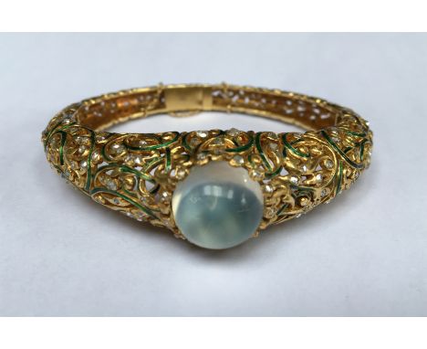 A HEAVY 18CT GOLD AND ENAMEL GEM SET BANGLE The hinged tapering bangle of pierced foliate design features elaborate intertwin