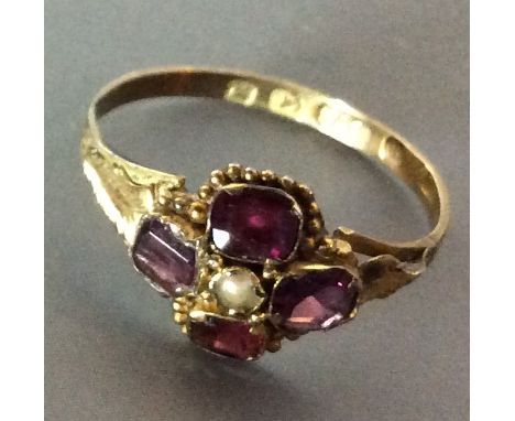 A VICTORIAN 9CT GOLD, GARNET AND SEED PEARL RING Having a single seed pearl surrounded by four square cut garnets and set in 