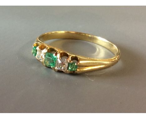 A VINTAGE 9CT GOLD, PERIDOT AND DIAMOND RING  Having three graduating peridots interspersed with diamonds, on a plain gold sh