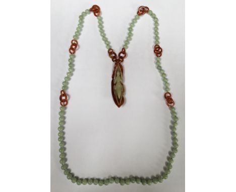 A TWO COLOUR JADE BEAD NECKLACE AND PENDANT  The pendant carved as a mantis on a leaf, suspended from a string of uniform gre