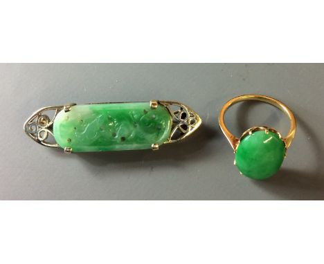 AN ORIENTAL 14CT GOLD AND JADE BAR BROOCH Having an oval jade panel, carved with a pierced and scrolled design and set in a t