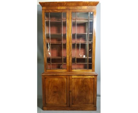A 19TH CENTURY MAHOGANY BOOKCASE With cushion cornice above two glazed doors and flame mahogany panelled doors below. (127.5c