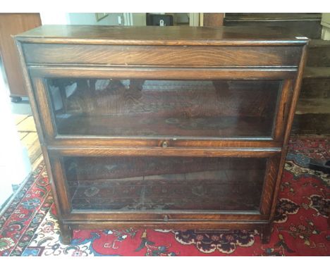 AN EARLY 20TH CENTURY OAK TWO SECTION BOOKCASE with folding glazed doors, in the style of globe wernicke  Measurements: 87 X 