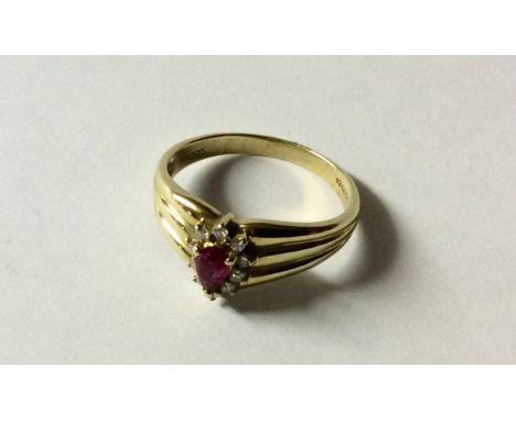 A HALLMARKED 9CT GOLD, RUBY AND DIAMOND DRESS RING The pear cut ruby claw set to a diamond surround between reeded shoulders,