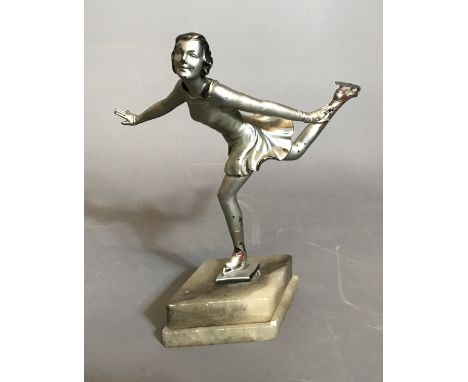 AN ART DECO COLD PAINTED SPELTER FIGURINE OF AN ICE SKATER  Wearing a silver costume with one foot aloft, raised on a lozenge