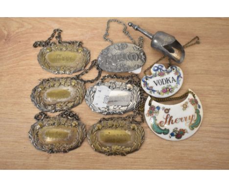 A collection of silver tone and enamel decanter labels, also included is a bottle stop.