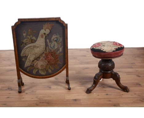 A late 19th Century oak embroidered fire screen, with shield-shaped frame, raised on four down swept legs, the embroidery dep