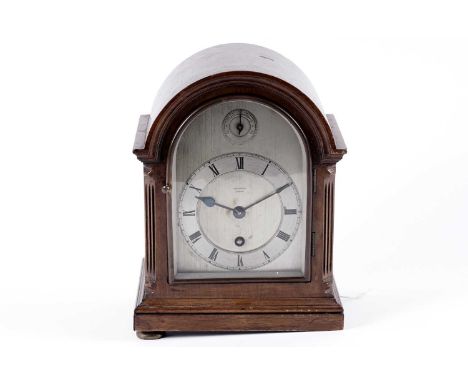 A mid-20th Century mantel clock retailed by Harrods London, the arched metal dial with a silvered chapter ring having Roman n