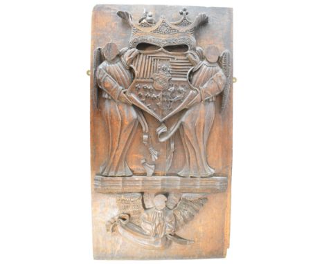 Continental carved oak armorial panel comprising a heraldic coat of arms being help by two winged angels with further angel b