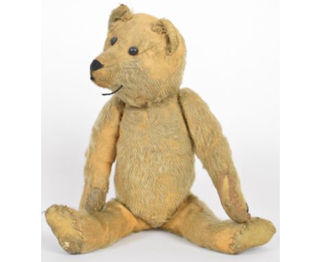 Early twentieth century straw filled Teddy bear with blonde mohair, stitched features, articulated head and limbs, leather pa