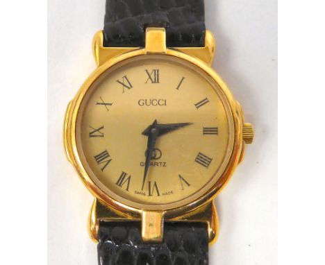 A lady's Gucci yellow metal wristwatch, the quartz movement faced by a Roman dial, on a dedicated black hide strap