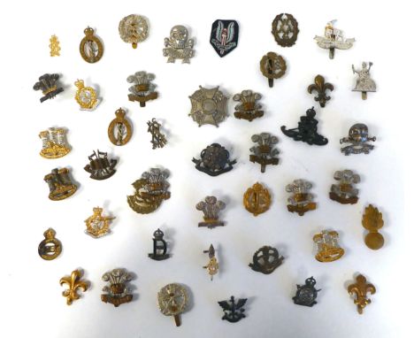 Approximately thirty-five British military cap badges: to include County of London Yeomanry; Lancashire Hussars; and The Welc