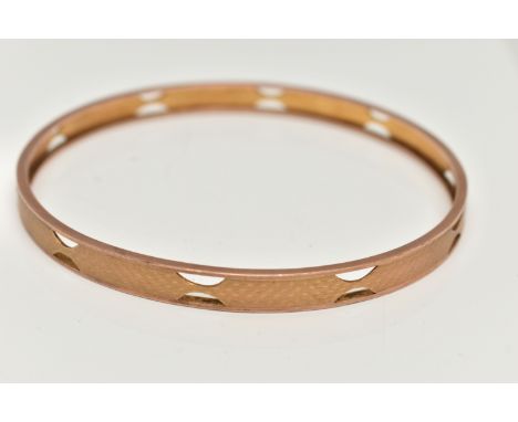 AN EARLY 20TH CENTURY ARM CUFF,  a rose gold bangle decorated with an engine turned pattern and pierced detail, approximate b